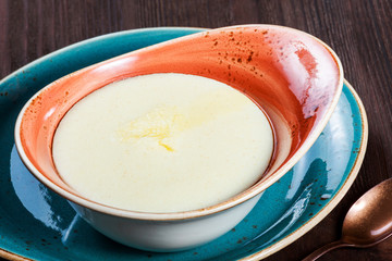 Bowl of semolina porridge with butter on dark wooden background close up. Hot and healthy breakfast, top view, flat lay