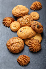 Assorted cookies with chocolate chip, oatmeal raisin on stone slate background on wooden background close up. Homemade baking. Top view, flat lay