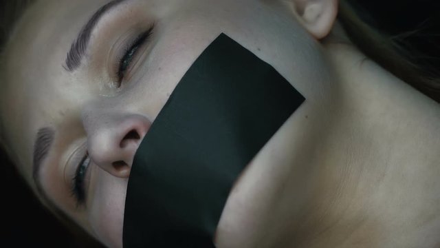 Young woman with taped mouth losing consciousness in trunk of car, kidnapping