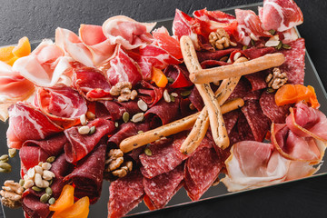 Antipasto platter cold meat with grissini bread sticks, prosciutto, slices ham, beef jerky, salami,...