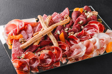 Antipasto platter cold meat with grissini bread sticks, prosciutto, slices ham, beef jerky, salami,...