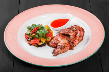 Grilled chicken and salad with grilled vegetables in plate on dark wooden background. Hot Meat Dishes. Top view, flat lay