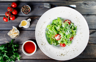 Fresh salad with mixed greens, cherry tomatoes, parmesan cheese on wooden background. Healthy food. Ingredients on table