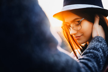 Hand of anonymous man touching face of beautiful young woman in stylish glasses and hat.Crop hand...