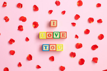 Word Love with rose petals on pink background. Sweet holiday background.
