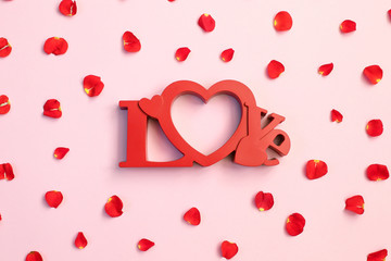Word Love with rose petals on pink background. Sweet holiday background.