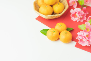 Top view aerial image shot of arrangement decoration Chinese new year & lunar new year holiday background concept.Flat lay fresh orange with pink cheery blossom & red pocket money on  white wooden.