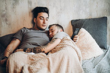 Perfect morning with beloved friend in bed. Two happy handsome guys resting in bed and watching...