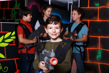 teen boy standing with laser pistol in dark lasertag room