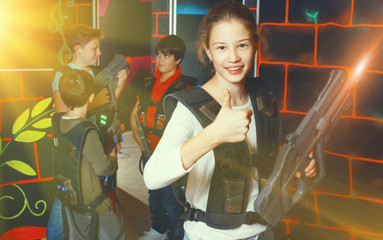 Cheerful teen girl standing with laser pistol in dark lasertag r