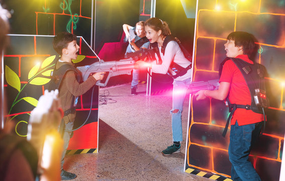 Group of happy teenagers with laser guns having fun on dark lase