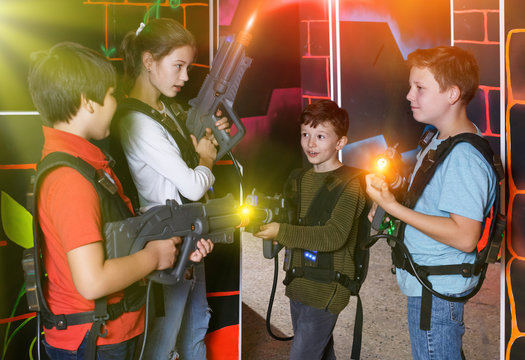 Joyful teens aiming laser guns at other players