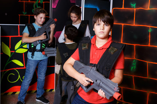 teen boy standing with laser pistol in dark lasertag room