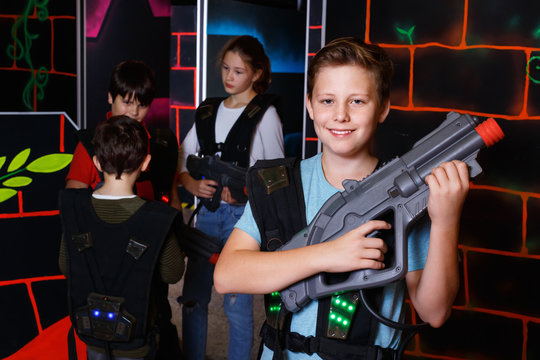 Portrait of preteen boy with laser pistol posing in laser tag la