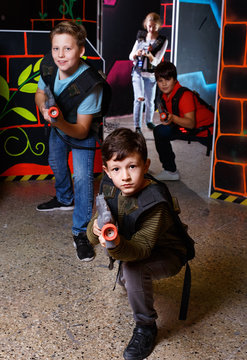 Portrait of preteen boy with laser gun having fun on dark lasertag arena