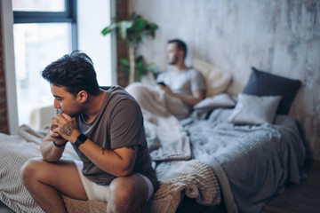 Same sex relationship problems. Close up of dark-haired handsome guy looking away with unhappy...