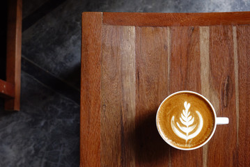 a cup of latte art coffee on wooden background