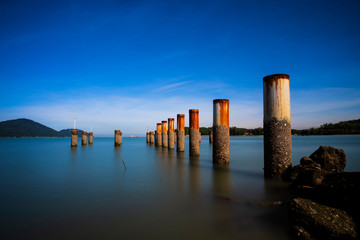 Naklejka na ściany i meble Abandon Piling Pier at Lumut,Malaysia With Smooth Water. Soft Focus,Blur Due To Long Exposure. Visible Noise Due To High ISO.