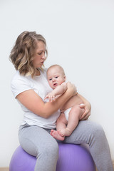 mother and her baby doing exercises on a ball