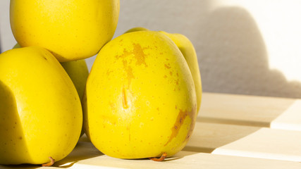 Many green apples on a shelf. A white, wooden background.