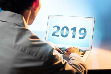 Businessman using laptop with 2019 number on the screen