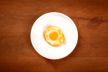 A photo of a quail egg, fried sunny side up, on a cracker, shot from the top on a dark rustic wooden background with a place for text
