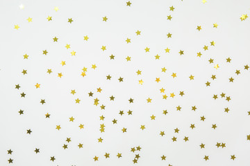 Golden star sprinkles on white. Festive holiday background. Celebration concept