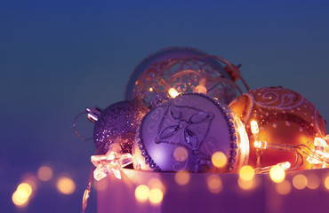 Image of christmas festive tree gold, purple and violet balls decoration in the gift box.