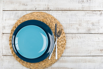empty blue dishes (plate, bowl) on a white wooden background (table), top view, copy space, mock-up