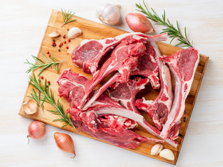 Raw lamb ribs on wooden chopping Board on white background, top view
