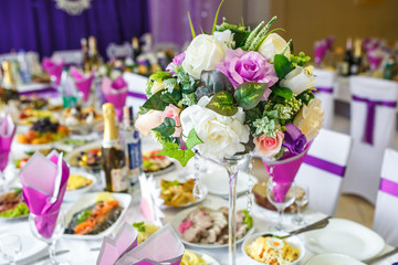 Beautiful flowers on elegant dinner table in wedding day. Decorations served on the festive table in violet background