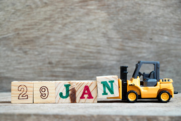 Toy forklift hold block N to complete word 29jan on wood background (Concept for calendar date in 29 month January)