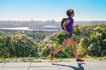 Woman runner run commutes to work with backpack, city morning run commuting and fitness concept,...
