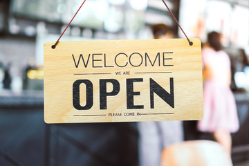 A business sign that says ‘Open’ on cafe or restaurant hang on door at entrance. Vintage color tone style.