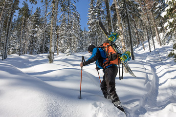 Asian man snowboarder freeride in snowshoes rises uphill in winter on snow