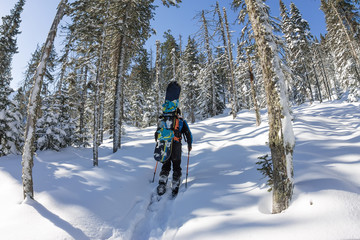 Asian man snowboarder freeride in snowshoes rises uphill in winter on snow