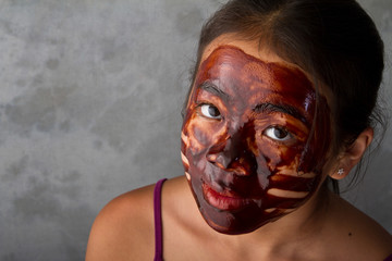 young asian girl having fun with a chocolate mask