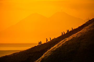 Fototapeta na wymiar Tourists hiking down a hill at sunset, Komodo Island, Indonesia