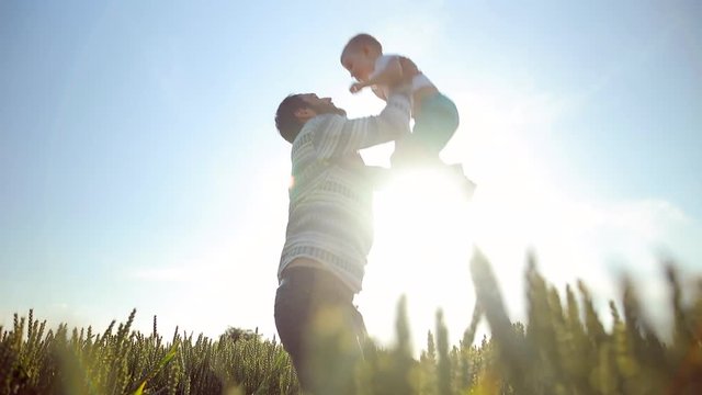 Strong father lobbed son in the sky. Playing with him at sunset in the wheat field