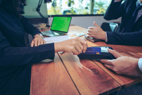 Close up of hand using credit card swiping machine to pay. Hand with creditcard swipe through terminal for payment in a restaurant. Man entering credit card code in swipe machine.