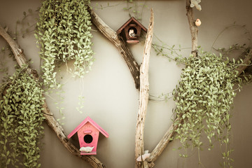 Wooden birdhouse in garden with hanging plant on concrete wall background