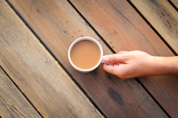 cup of coffee in hand  on the wooden table