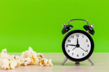 Popcorn and small alarm clock on pastel green background minimal creative concept. Space for copy.