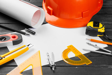 Close up orange hardhat and variety of repair tools with copy space in the middle over wooden  background