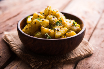 Jeera Aloo is a Indian main course dish which goes well with hot puris, chapatti, roti or dal. served in a bowl over moody background. selective focus