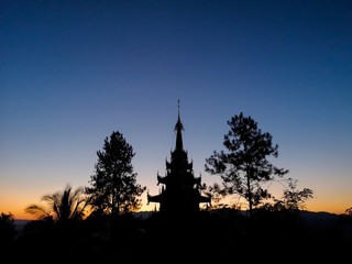 Obraz premium Buddhist pagoda silhouette with trees at sunset