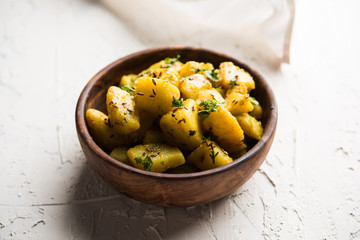 Jeera Aloo is a Indian main course dish which goes well with hot puris, chapatti, roti or dal. served in a bowl over moody background. selective focus