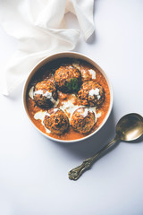 Malai Kofta is a Mughlai Speciality dish served in a bowl or pan over moody background. selective focus