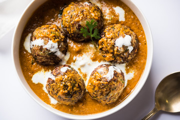 Malai Kofta is a Mughlai Speciality dish served in a bowl or pan over moody background. selective focus