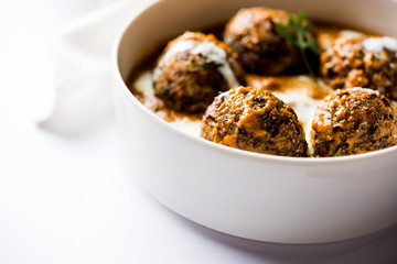 Malai Kofta is a Mughlai Speciality dish served in a bowl or pan over moody background. selective focus